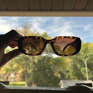 Chic Prada sunglasses with a classic tortoise pattern. Ideal for stylish sun.
